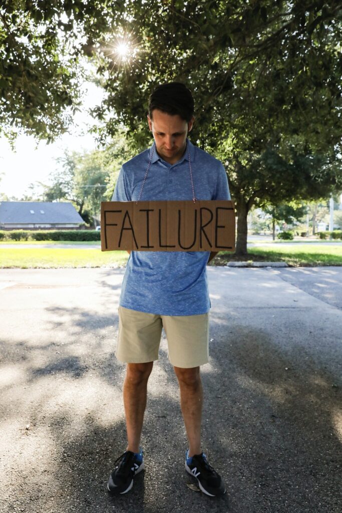 Letting go of perfectionism: Man wearing a sign with the word "failure".